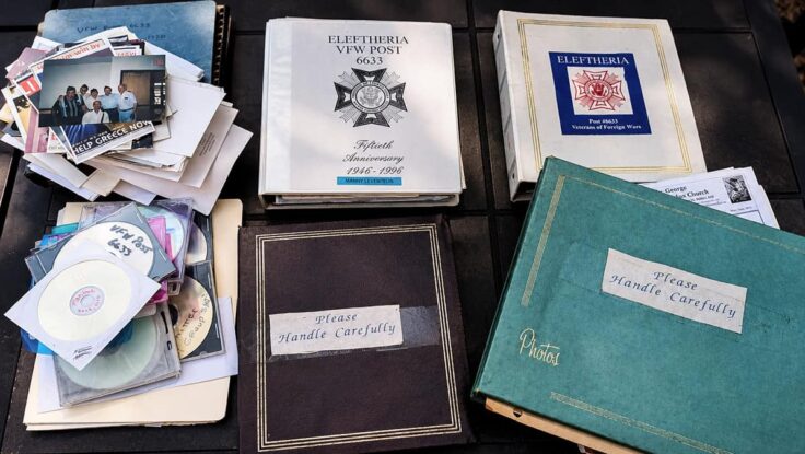 Eleftheria VFW Post 6633 albums, discs, photographs, and archive materials spread across a table.